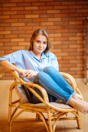 young woman relaxing in a big comfortable chairの写真素材