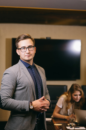 businessman looking at camera with blurred workers on backgroundの写真素材