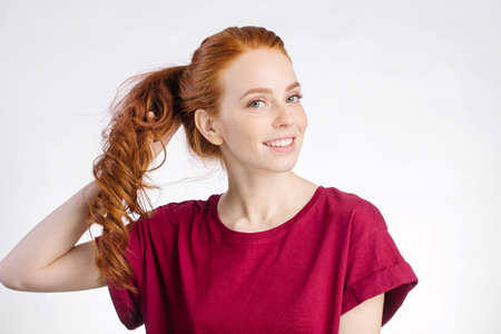 redhead woman holding her healthy and shiny hair, studio whiteの写真素材