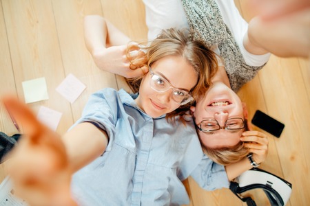 Couple studying while lying on floor at homeの写真素材