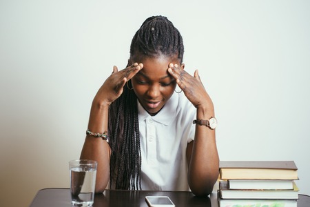 african young woman sitting at table with books at homeの写真素材