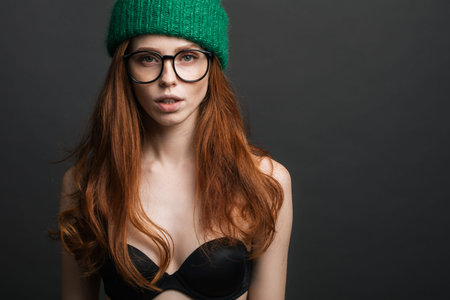 fashion redhead Girl in Knitted Hat and galsses on grey background