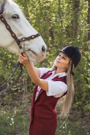 beautiful brunette girl with long hair posing with a red horse in forestの写真素材