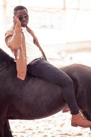 man riding brown horse on countrysideの写真素材