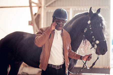 african Man wearing sunglasses near black horse in hangarの写真素材