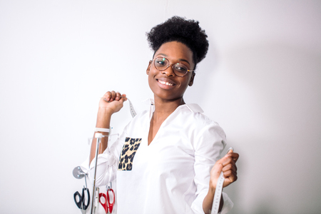 smiling seamstress looking at camera with sewing machineの写真素材