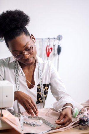 african seamstress working with fabric takes measures