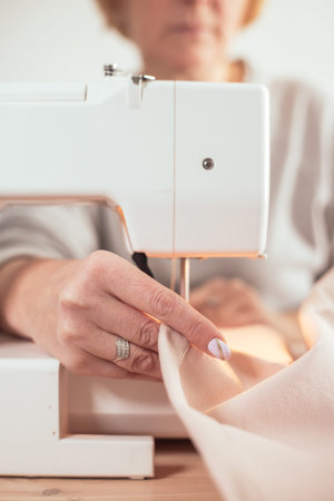 Close-up african seamstress hands working on sewing machine at home
