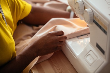 Close-up seamstress hands working on sewing machine at homeの写真素材