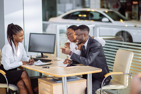 happy african couple with dealer buying car in auto show or salonの写真素材