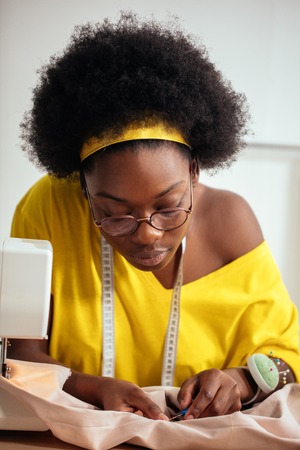 sewing fabric with needle at seamstress workplaceの写真素材