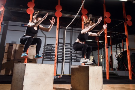 Fit young woman box jumping at a cross fit gymの写真素材