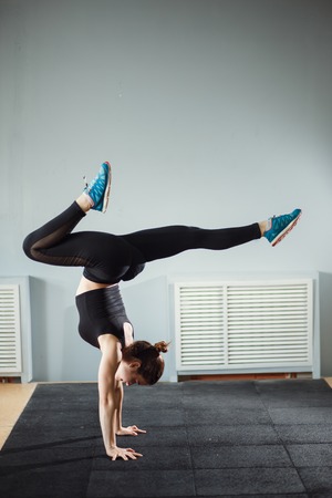 woman working out against grey wall, doing yoga or pilates exerciseの写真素材