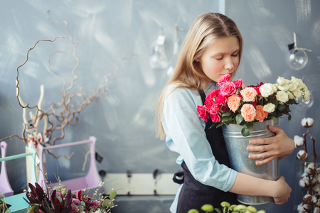 girl with long fair hair hugging and smelling white and pink rosesの写真素材