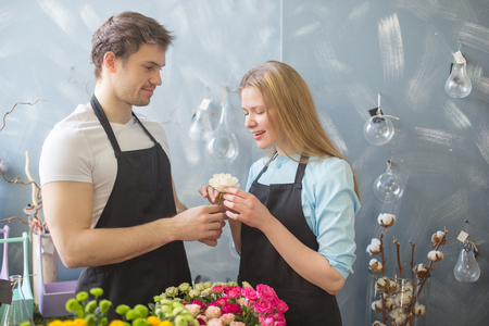 handsome guy presenting white rose to his girl indoorの写真素材