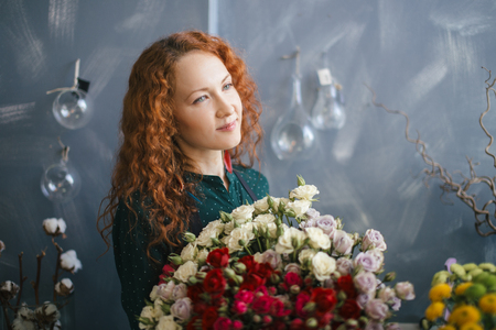 saleswoman with charming appearance holding bouquet of red and white rosesの写真素材