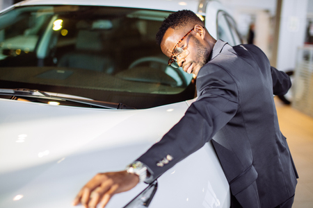 Handsome black man is hugging his new car and smilingの写真素材