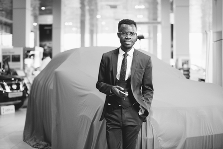 african car salesman using smart phone in showroomの写真素材