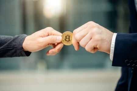 Businessman giving bitcoin to another person. hands exchanging cryptocurrencyの写真素材
