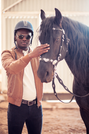 african Man wearing sunglasses near black horse in hangarの写真素材