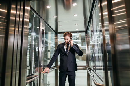 Business man walking while talking on mobile phone on his way to workの写真素材