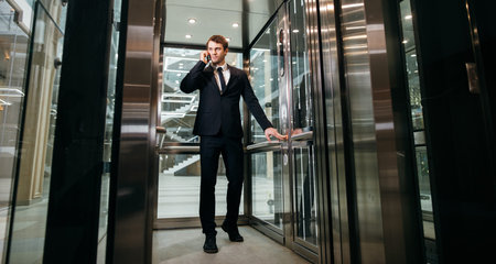 Business man walking while talking on mobile phone on his way to work