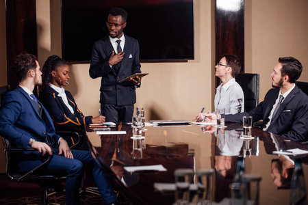 African American business man giving presentation to associates