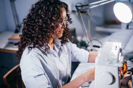 close up side view shot of tailor making stitching with sewing machineの写真素材