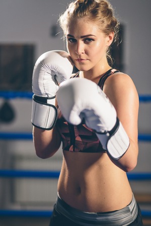 Female Boxer wearing gloves posing in boxing studioの写真素材
