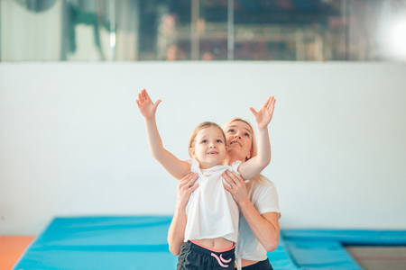 Mother helping daughter to play sports on gymnastic ringsの写真素材