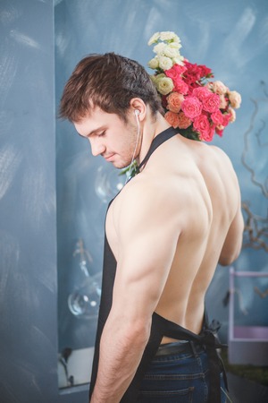 naked torso of salesman with bouquet of flowers holding behind back on blueの写真素材