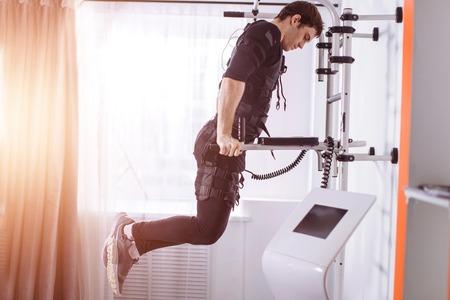 EMS male working out, doing push ups. man doing triceps dips on parallel barsの写真素材