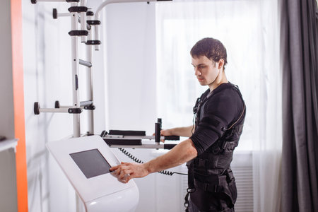 athlete regulating intensity of ems electro muscular stimulation machine