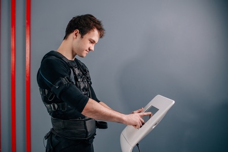 athlete regulating intensity of ems electro muscular stimulation machineの写真素材