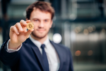 Bitcoin in hand with businessman blurred on backgroundの写真素材