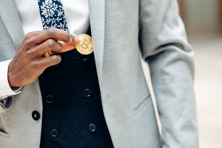 African Man pick bitcoin from suit pocket . Man puts bitcoin in pocketの写真素材