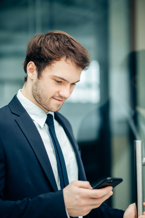 businessman with smartphone over office buildingの写真素材
