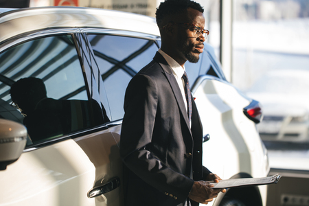 Handsome african car salesman standing at the dealership holding a tabletの写真素材