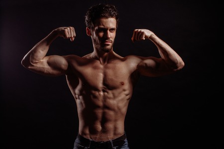 young man with naked body bending elbows the bicepsの写真素材