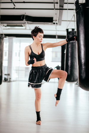 athlete in black sporty shorts and top standing with raised bent knee on one legの写真素材