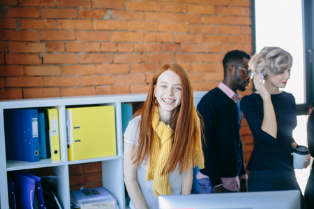 slim ginger woman with long straight hair is looking at the cameraの写真素材