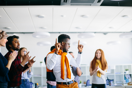 african male is dancing with raised fingers while his friends are clapping handsの写真素材