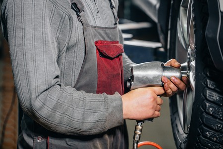 mechanic screwing or unscrewing car wheel by pneumatic wrenchの写真素材