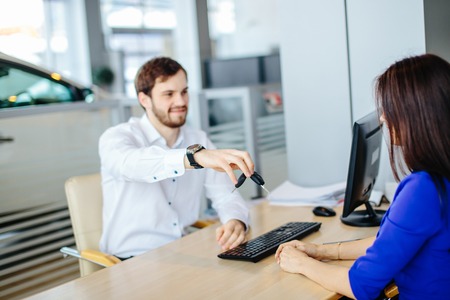 Positive young seller man handing over car key to ner ownerの写真素材
