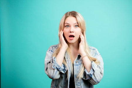 Portrait of surprised blonde woman in denim jacket