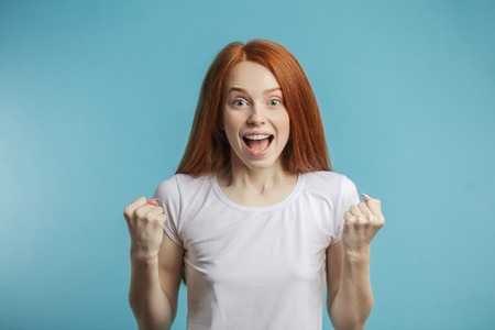 Female model with red loose hair and natural make-up posing over blue background.の写真素材