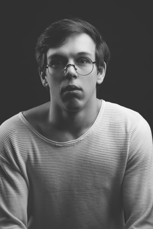 close up photo of pensive nerd in round glasses looking at the cameraの写真素材