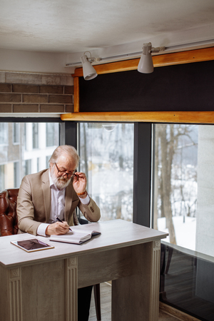 side view shot of old grey-haired teacher preparing for lectureの写真素材