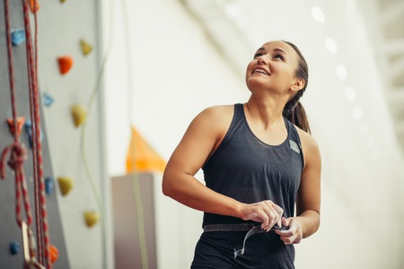 young woman with chalked hands posing at indoor climbing gym wallの写真素材
