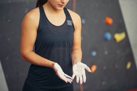 young woman with chalked hands posing at indoor climbing gym wallの写真素材